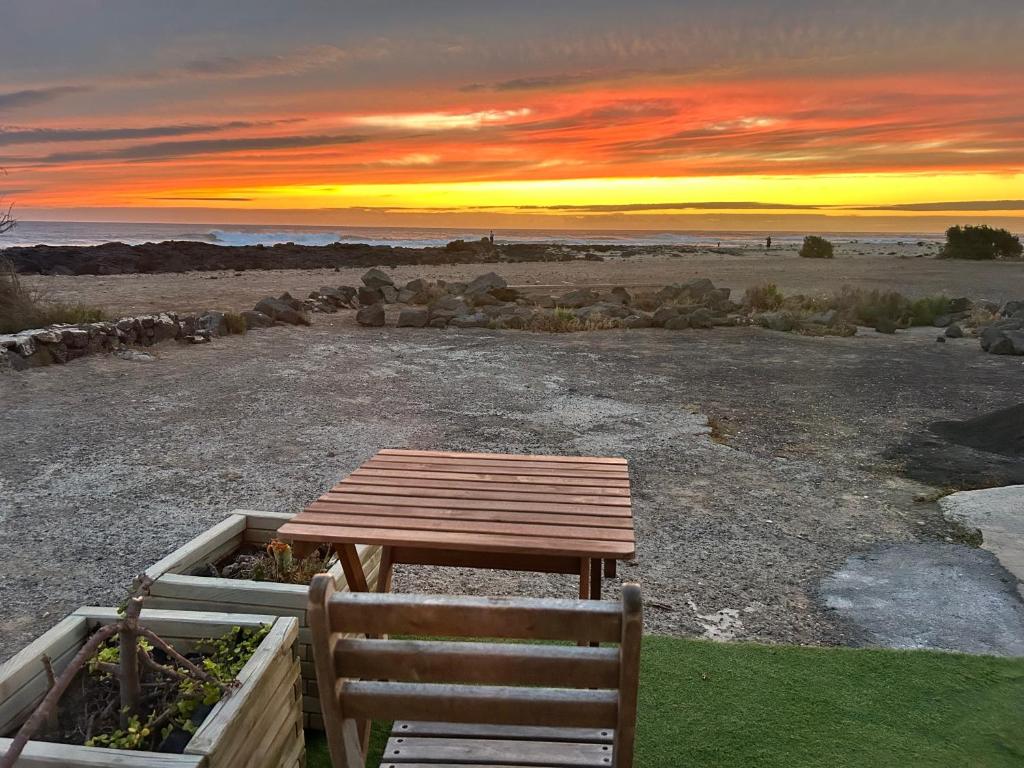 a wooden table and chair in a field with a sunset at El Cotillo Mar Sea View in El Cotillo