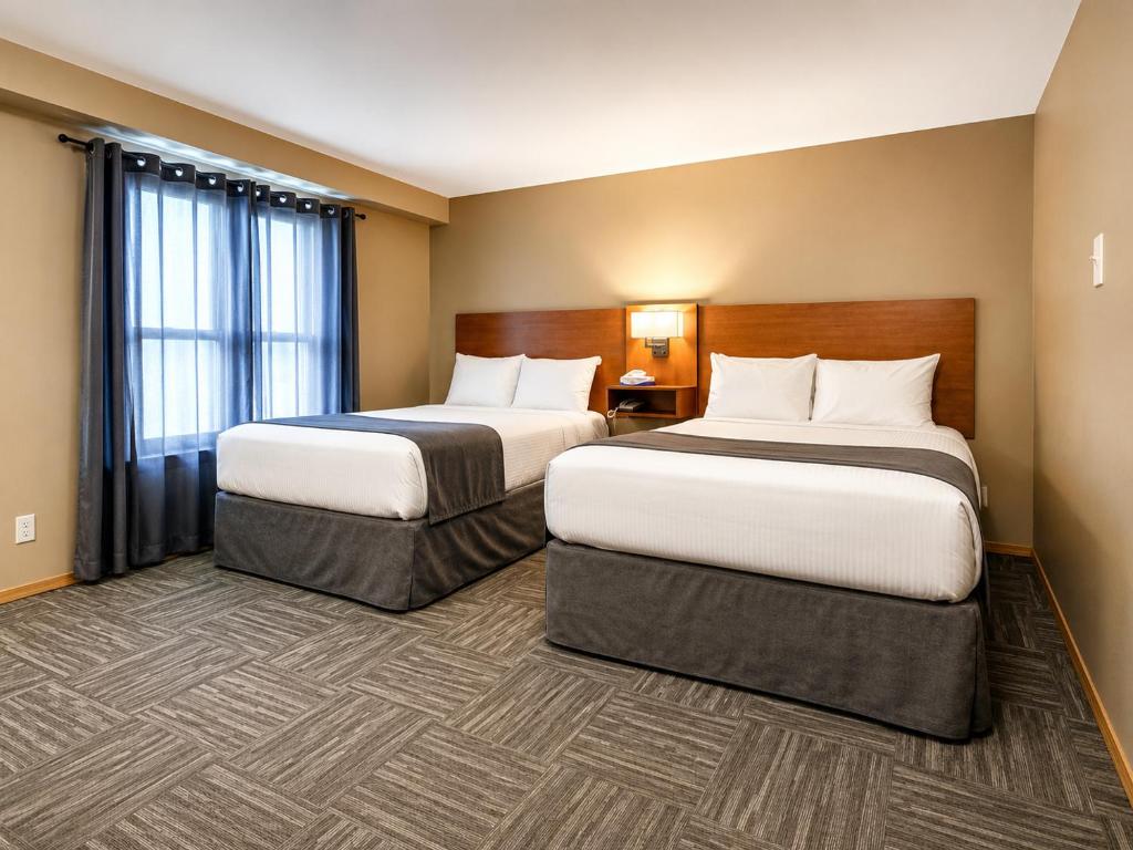 a hotel room with two beds and a window at Ste Anne Hotel in Sainte Anne-des-Chênes
