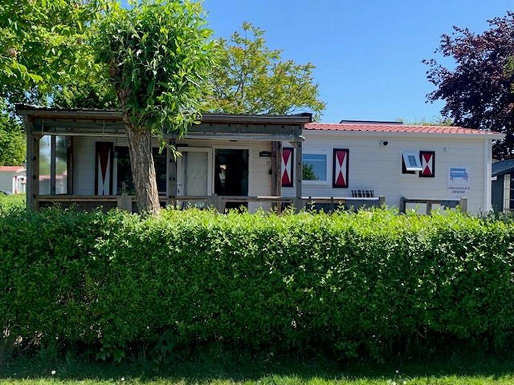 a house with red and white decorations in front of a hedge at Lieblingsplatz Renesse, Camping Siblu de Oase in Renesse
