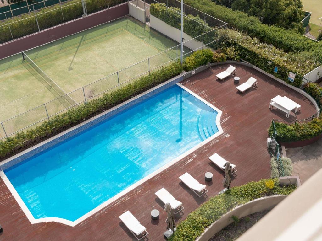 Draufsicht auf ein Schwimmbad mit Tennisplatz in der Unterkunft Mercure Sydney Parramatta in Sydney