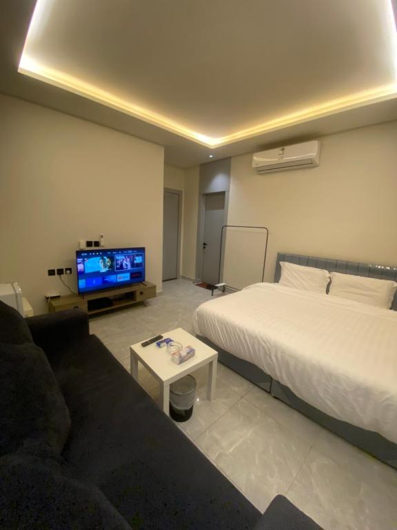 a bedroom with a bed and a couch and a tv at Condo in Alramal near to the airport in Riyadh