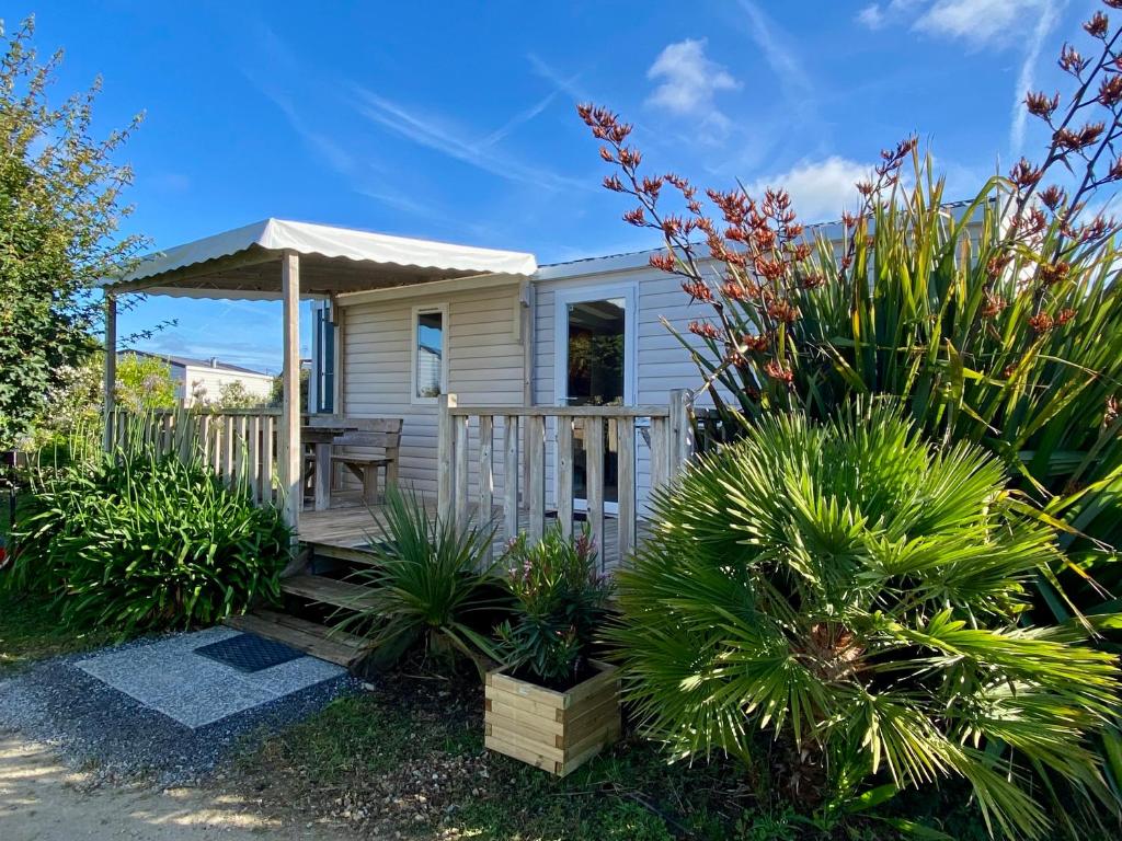 a small yellow house with a porch and a gazebo at Mobilhome camping St jacques in Sarzeau