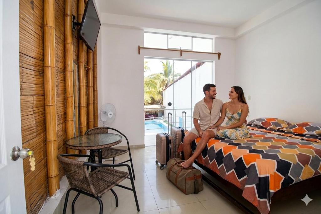 a man and a woman sitting on a bed at Sumarfe in Máncora
