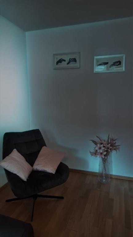 a living room with a black chair and a vase of flowers at Messe-Badische SBB- grosse Wohnung in Basel