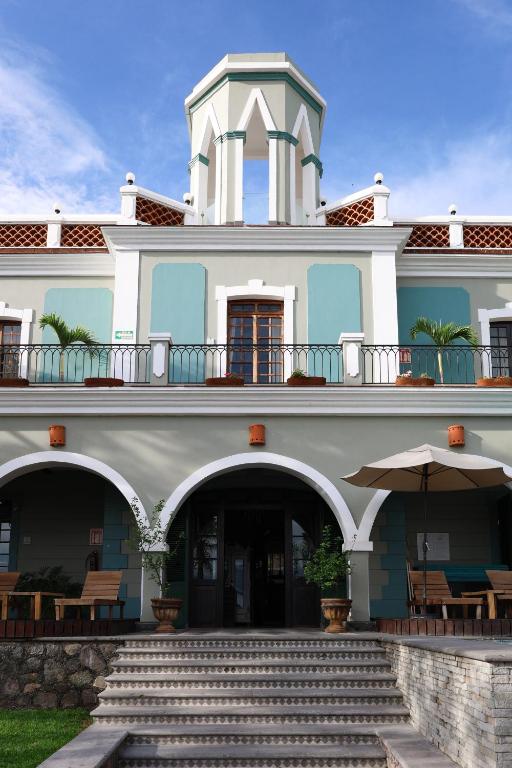 ein Gebäude mit einem Balkon und einer Treppe davor in der Unterkunft Hotel Villa 1927 in Chapala