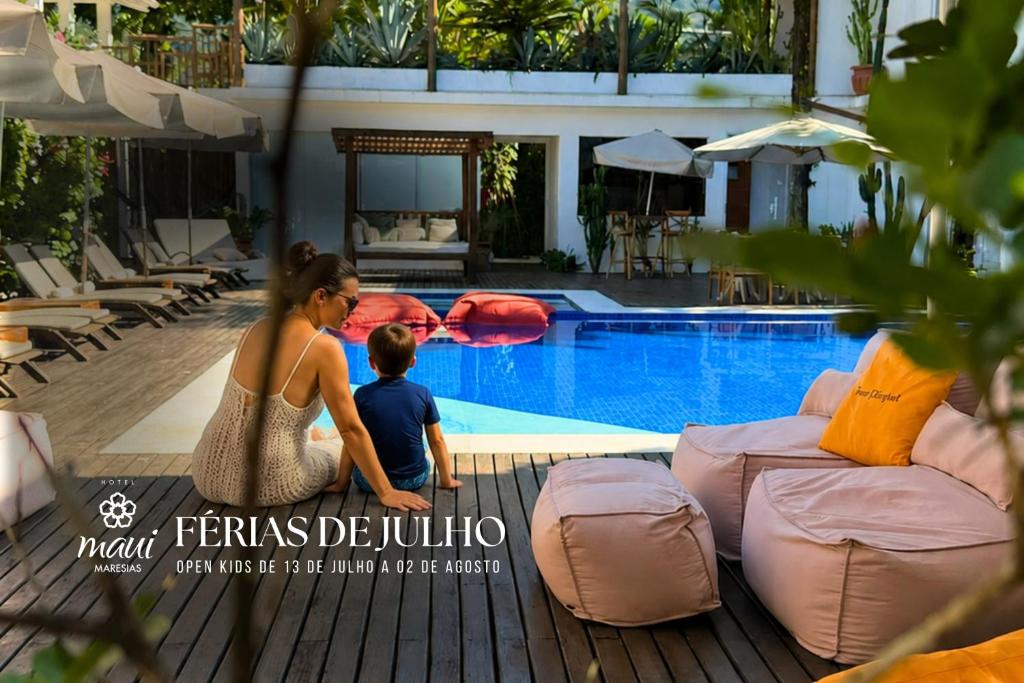 a woman and a child standing next to a swimming pool at Hotel Maui Maresias in Maresias