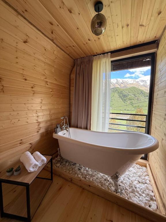 a bath tub in a wooden bathroom with a window at Tera Cottages kazbegi in Kazbegi