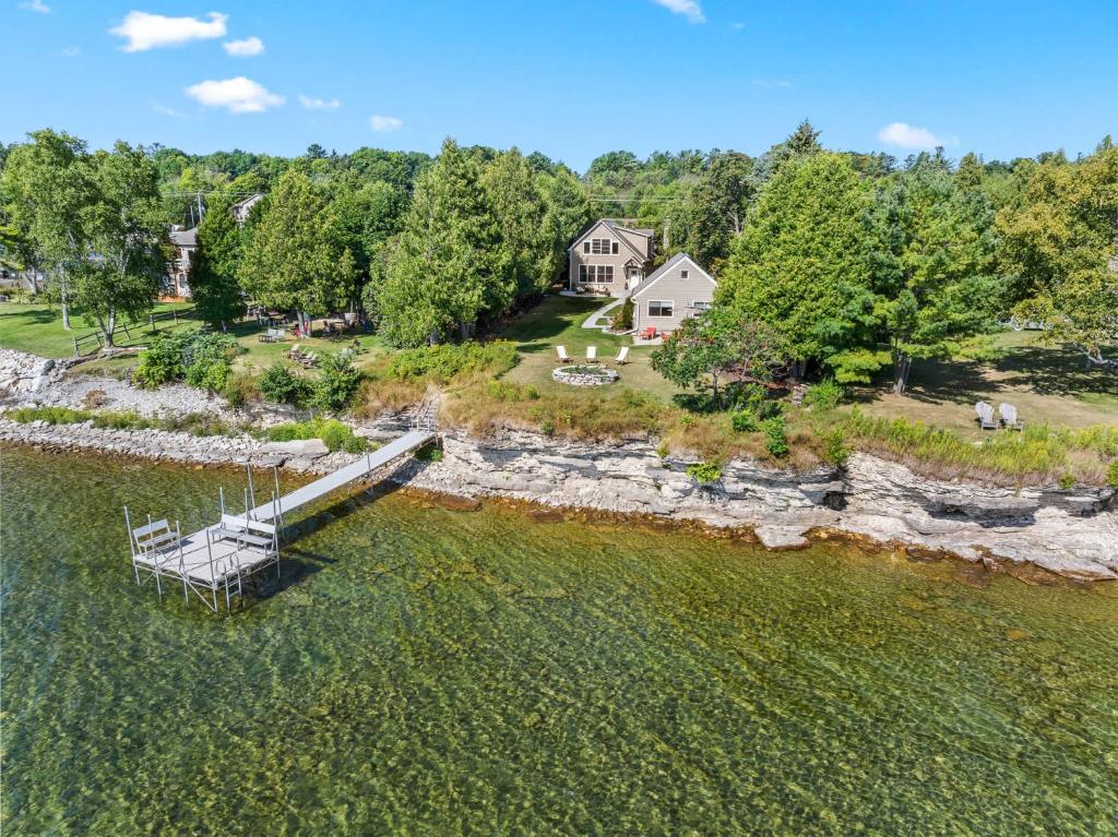 an aerial view of a house and a dock in the water at Limestone Edge by Simple Life Rentals in Baileys Harbor