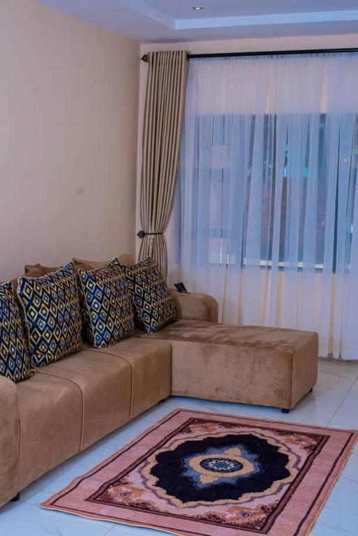 a living room with a brown couch and a rug at Mirai Apartments in Harare