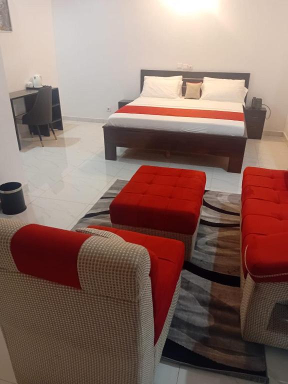 a bedroom with a bed and two chairs at HOTEL DU PRINCE Bingerville in Bingerville