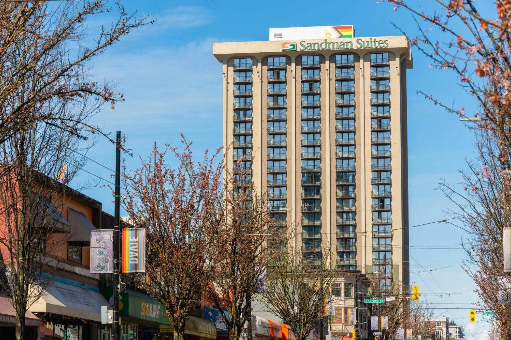 a tall building with a sign on top of it at Sandman Suites Vancouver on Davie in Vancouver