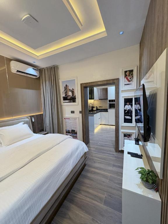 a bedroom with a large bed and a kitchen at Maydec Plus Homes & Apartments in Abuja