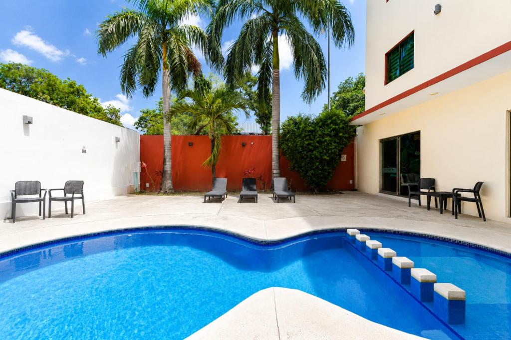 a swimming pool next to a house with palm trees at Hotel Ambra in Playa del Carmen