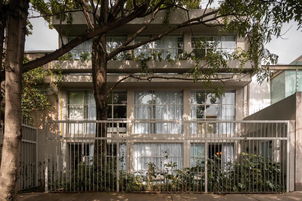 a building with a fence and a tree at Casa Levora in Mexico City