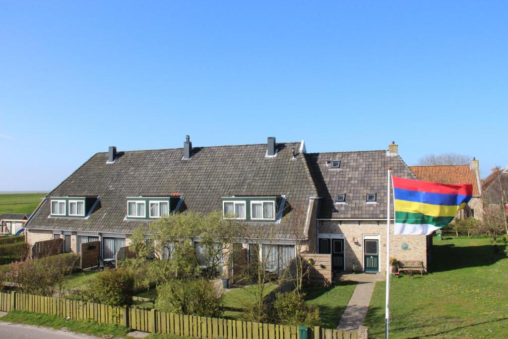 ein großes Haus mit einer Regenbogen-Flagge im Hof in der Unterkunft De Groede in Oosterend