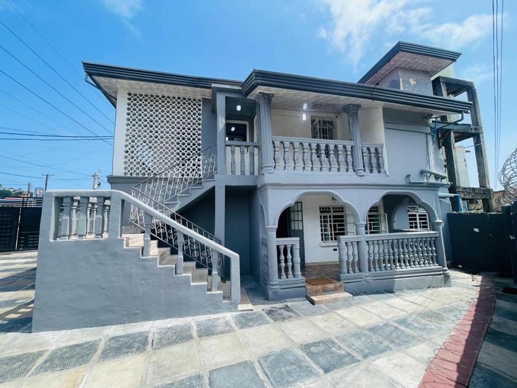 a white house with a balcony and stairs at Nic's Inn in Freetown