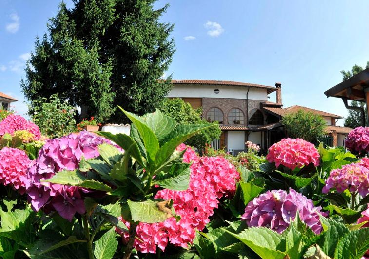 a garden with pink flowers in front of a house at Bed & Breakfast Villa Chiara in Magenta