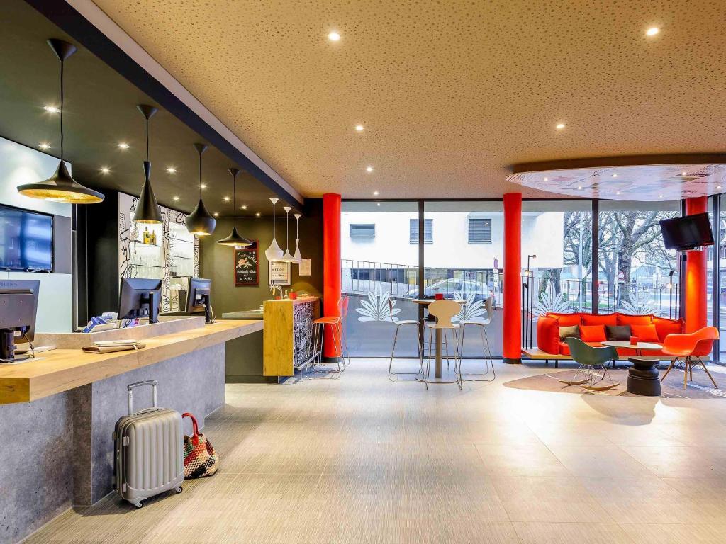an office with a lobby with orange chairs and a counter at Hotel Ibis Bregenz in Bregenz