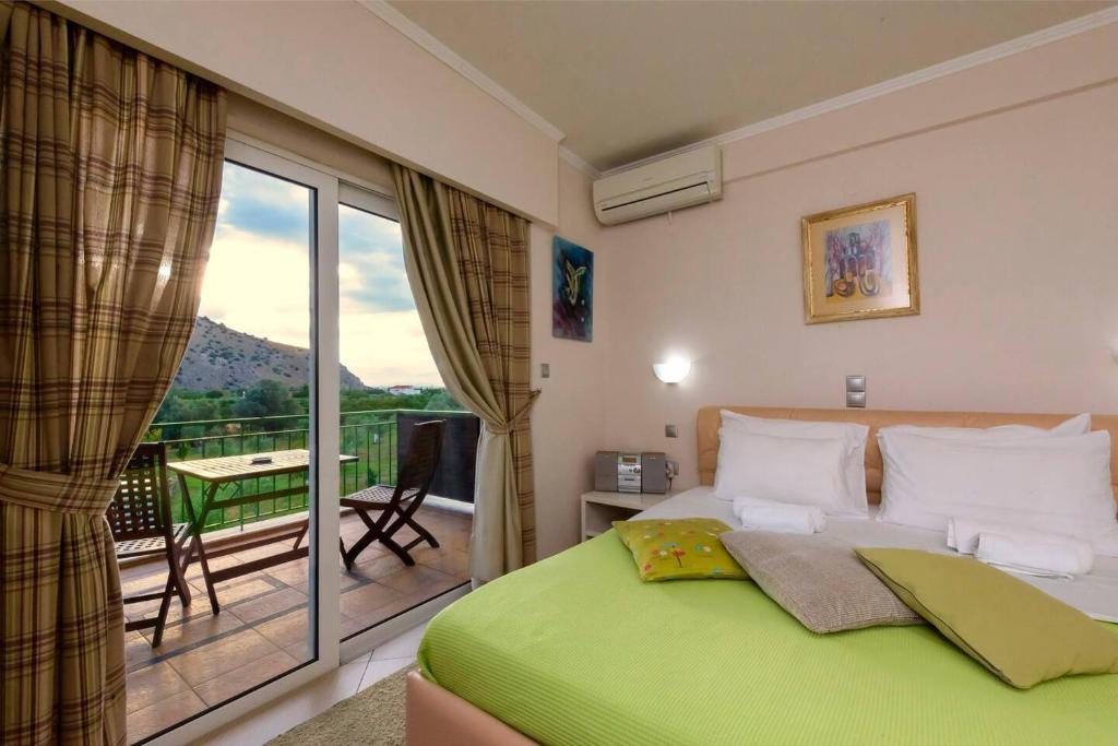a bedroom with a green bed and a balcony at Ktima Anastasia Olive Grove Nafplio in Nafplio