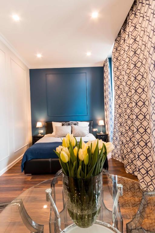 a bedroom with a bed and a vase of flowers on a table at LivingRoom Grand 1 self Check-in 24h in Katowice