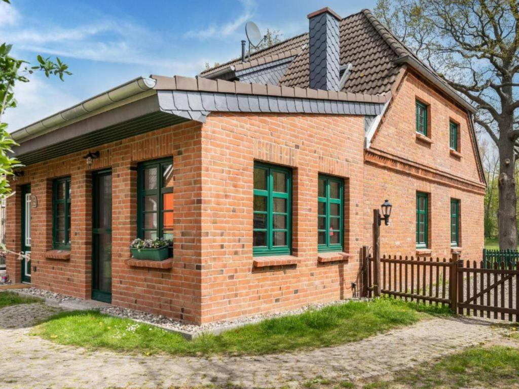 a brick house with green windows and a fence at Alma in Zierow