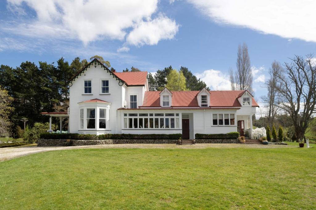a large white house with a red roof at Ashcott Homestead Bed & Breakfast in Takapau