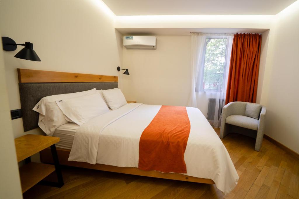 ein Schlafzimmer mit einem Bett, einem Stuhl und einem Fenster in der Unterkunft MIST Boutique Hotel in Yerevan