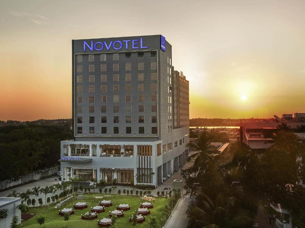 a novation hotel with cars parked in a parking lot at Novotel Chennai Sipcot in Chennai
