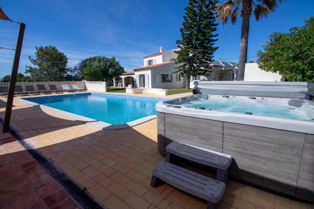 a pool with a hot tub and a bench next to a house at Villa Ursa by Algarve Holidays in Praia do Carvoeiro