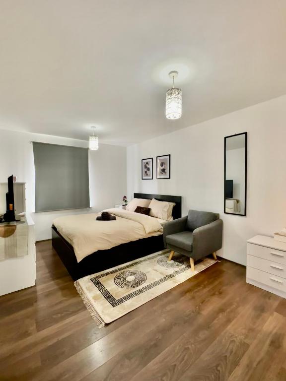 a white bedroom with a bed and a chair at Stay in Stratford in London