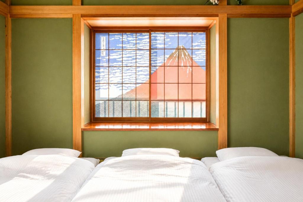 a room with three beds in front of a window at Fuji Nest Izu in Izunokuni