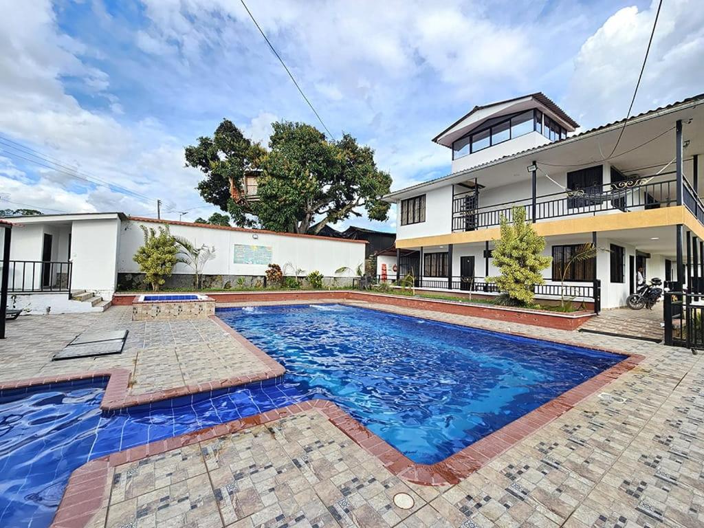 a swimming pool in front of a building at FINCA HOTEL GUADUAL Quindío in Quimbaya