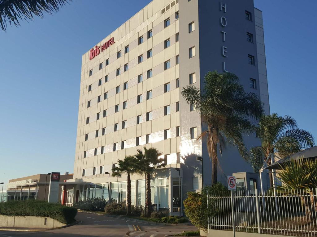 a tall building with palm trees in front of it at ibis Itu Plaza Shopping in Itu