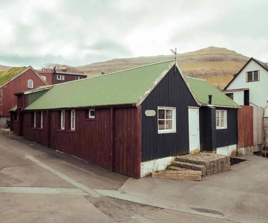 a red and black building with a green roof at Jógvansstova - 2BR House - Explore the North in Leirvík