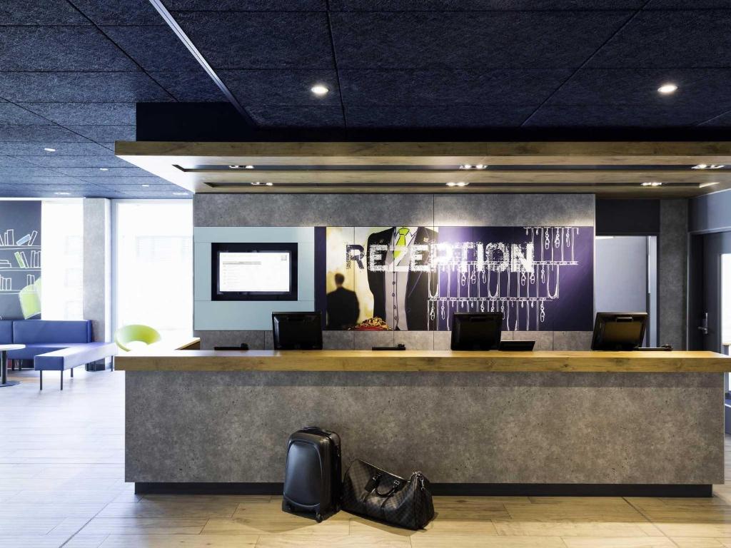 a lobby with a reception counter with black shoes at ibis budget Zurich Airport in Glattbrugg