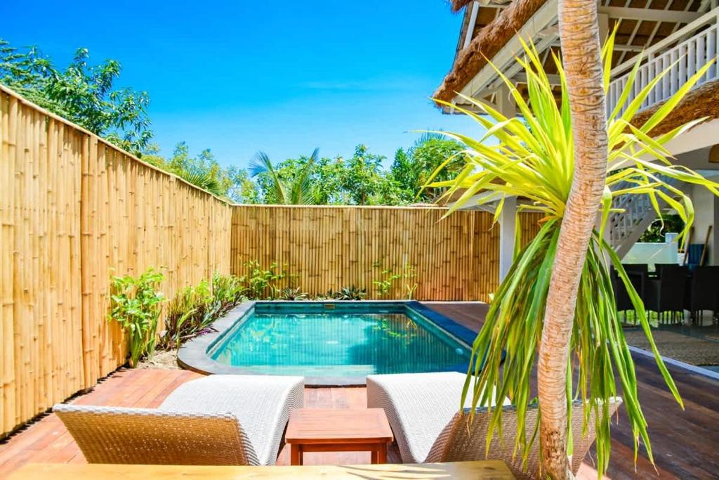 a swimming pool with chairs and a fence at Villa Asmara Gili Air in Gili Islands