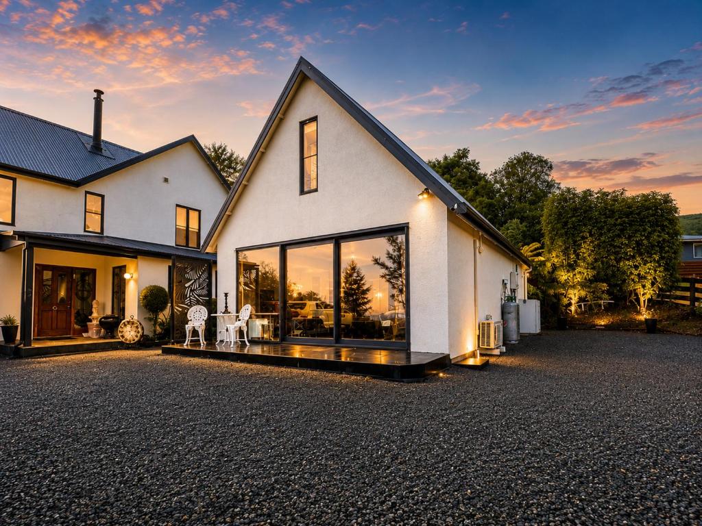 a white house with large windows on a driveway at Lake Brunner Chalet in Moana
