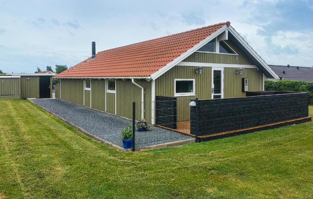 a small green house with a fence in front of it at 3 Bedroom Amazing Home In Haderslev in Haderslev