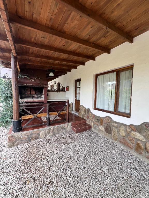 an outdoor living room with a wooden ceiling and a fireplace at Cabañas El Campo in Sierra de la Ventana