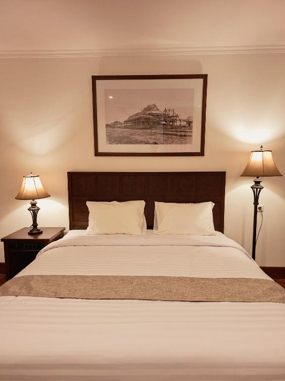 a bedroom with a large bed with two lamps at Hotel Butik Sawunggaling in Bandung
