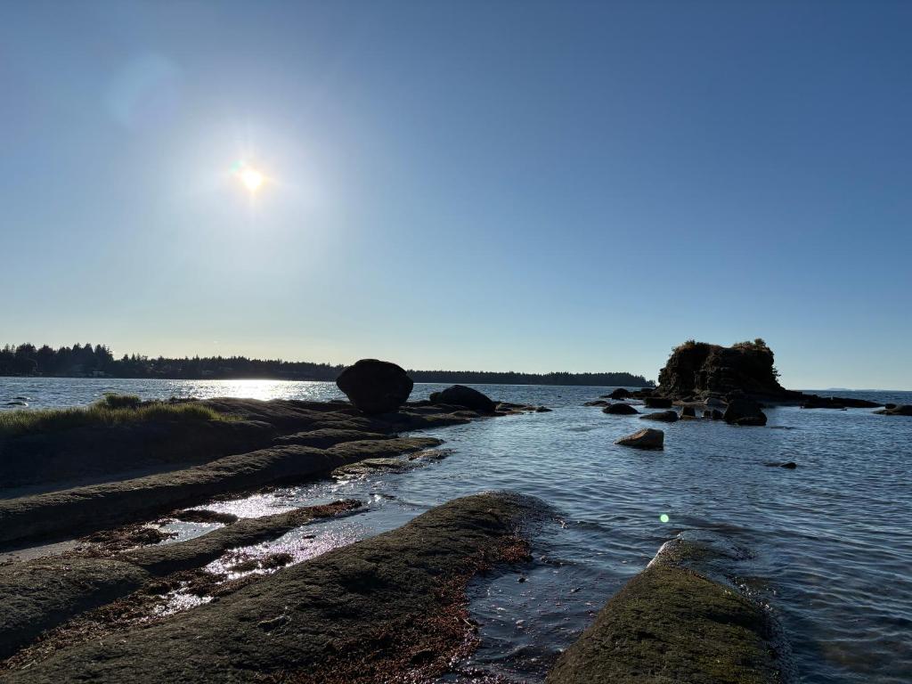 a body of water with the sun in the sky at Oceanside Getaway in Nanoose Bay