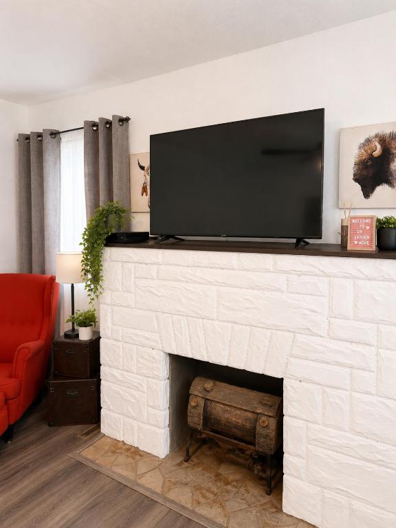a living room with a white brick fireplace with a flat screen tv at The sunflower stay in Garden City