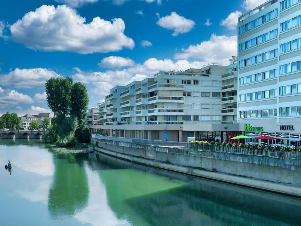 a building next to a river next to a building at ibis Styles Meaux Centre in Meaux