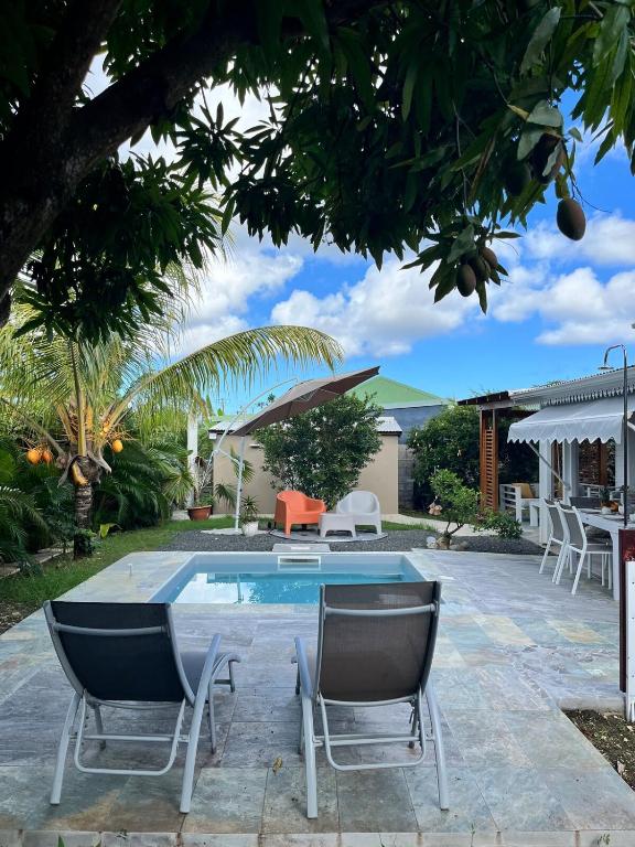 a patio with a table and chairs and a pool at Villa Odeyssia in Sainte-Anne