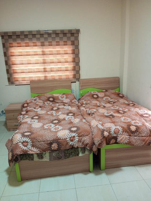 a bed with a comforter in a room with a window at عمان in Az Zarqa