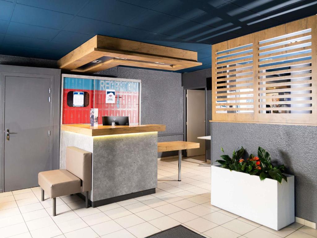 a restaurant lobby with a counter and blue ceilings at Ibis budget Périgueux in Périgueux