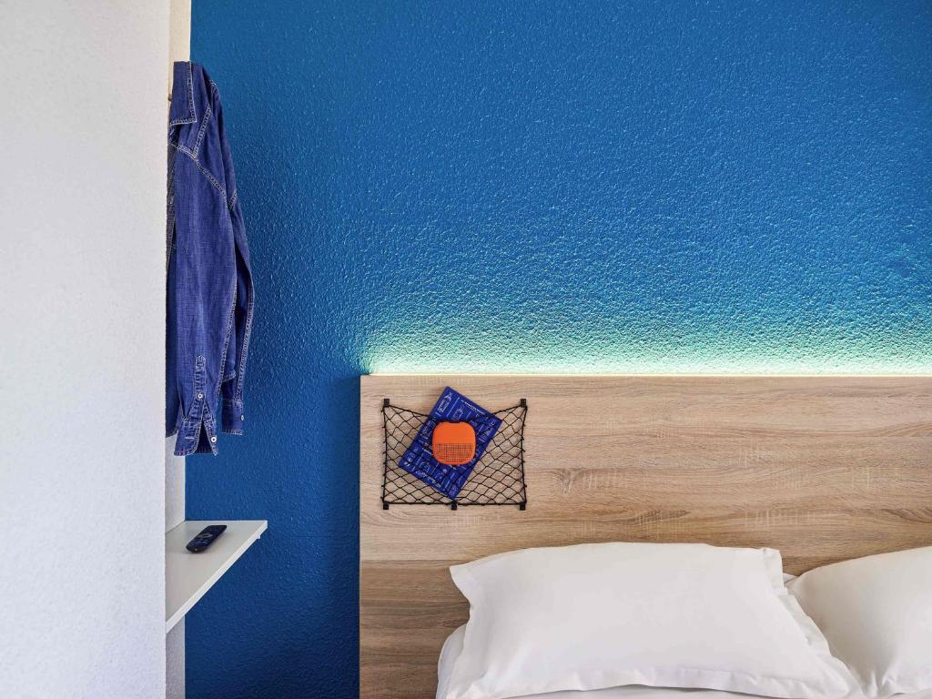 a bedroom with a blue wall and a bed at hotelF1 Paris Saint Denis Stade in Saint-Denis