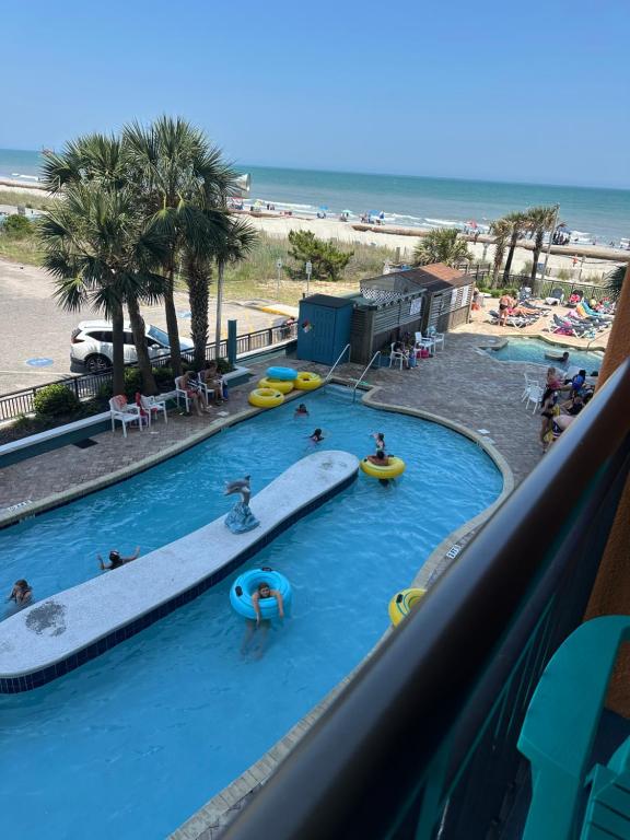 a pool with a surfboard and people in the water at Ocean View 2 Queen Studio at Landmark Resort in Myrtle Beach