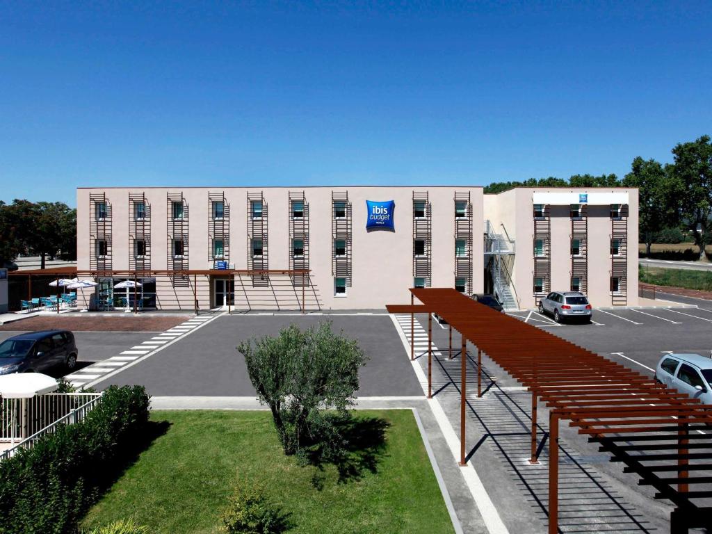 a large white building with a parking lot at Ibis Budget Manosque Cadarache in Manosque