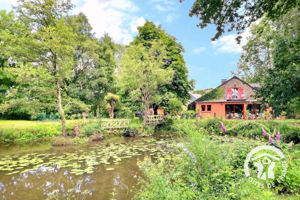 a house with a pond in front of a building at Le moulin de blochet in Saint-Erblon